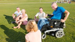 group of people outside in sunshine, one in a wheelchair
