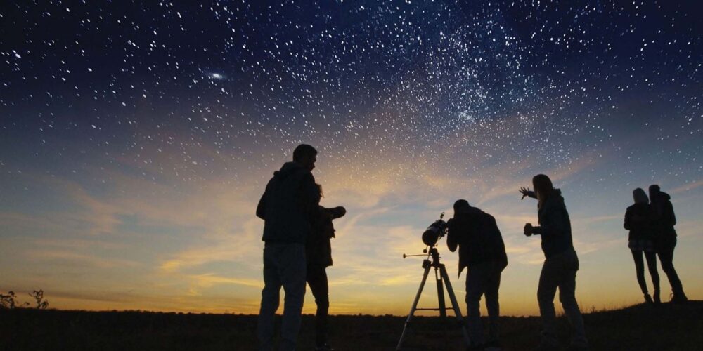 Curtin University researchers observing the night sky through a telescope