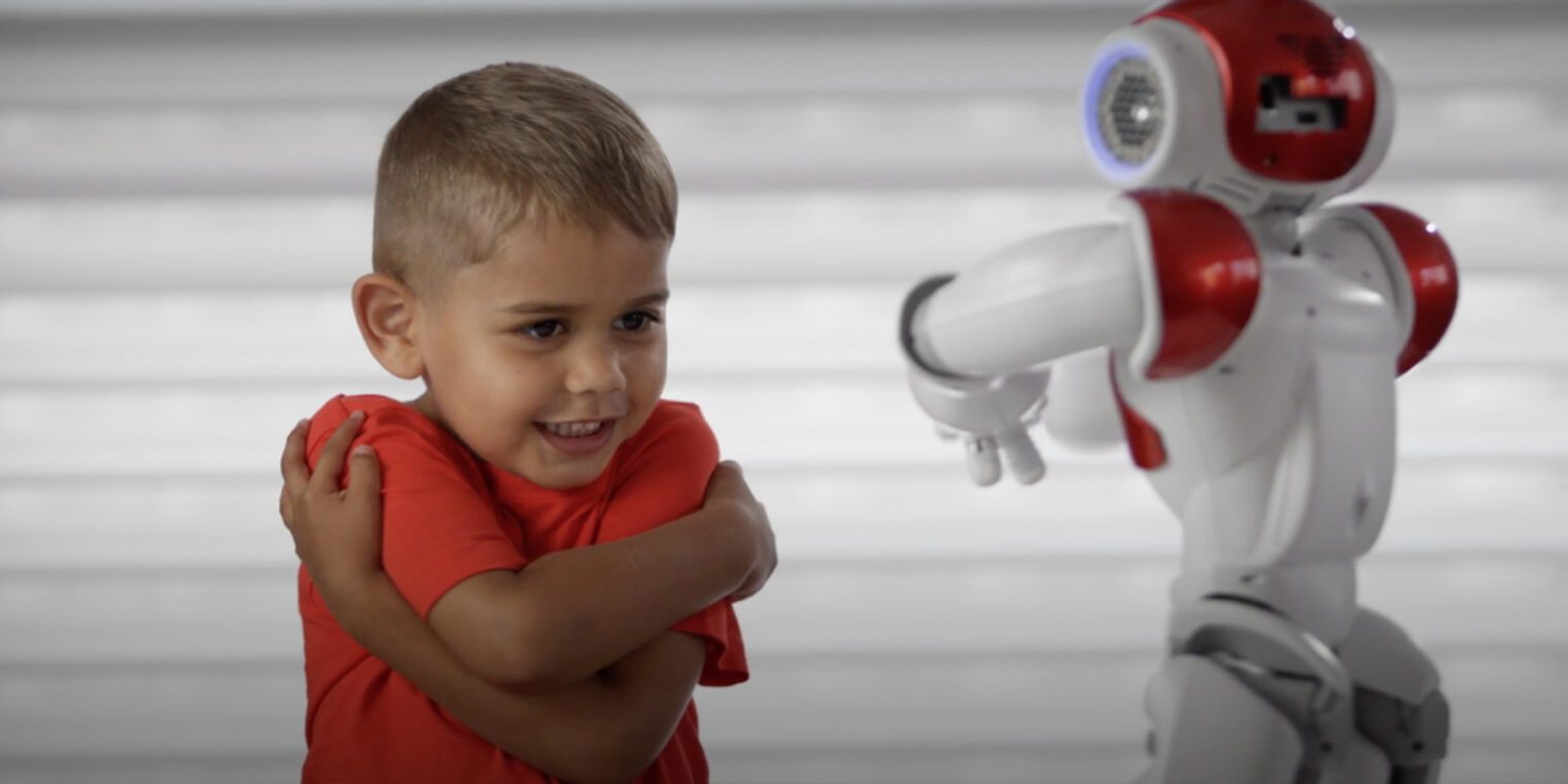Young boy interacting with a small humanoid robot - play video
